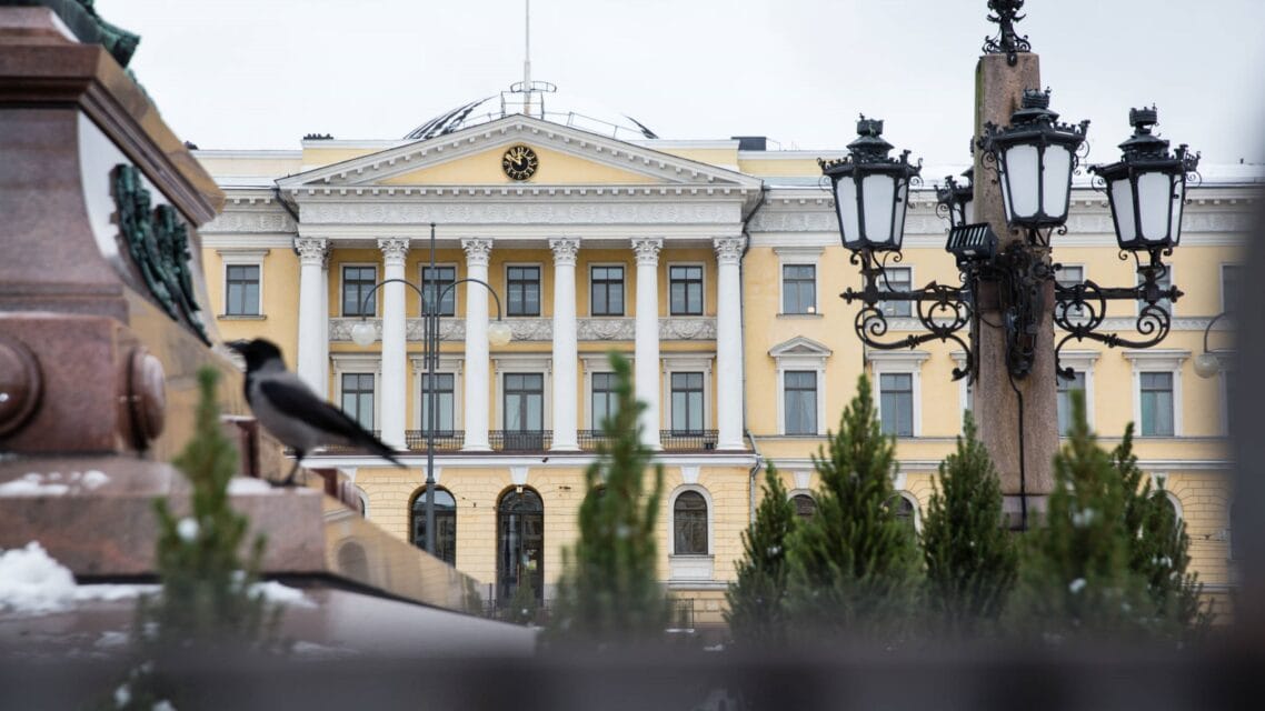 Valtioneuvoston rakennus Senaatintorilta kuvattuna, etualalla patsas ja lyhtypylväs.